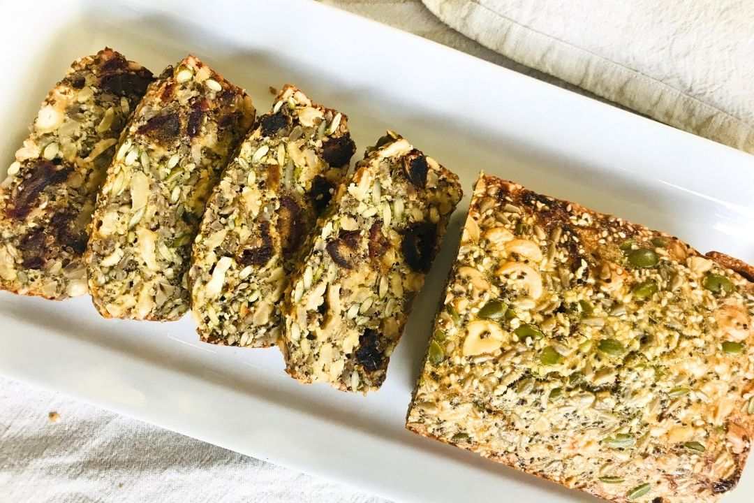 flat lay of half a loave of seed bread recipe that half is cut into 4 slices
