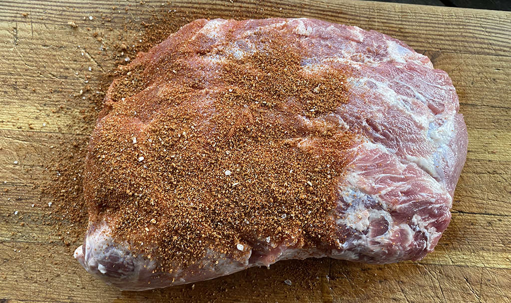 applying a dry spice rub to a pork scotch