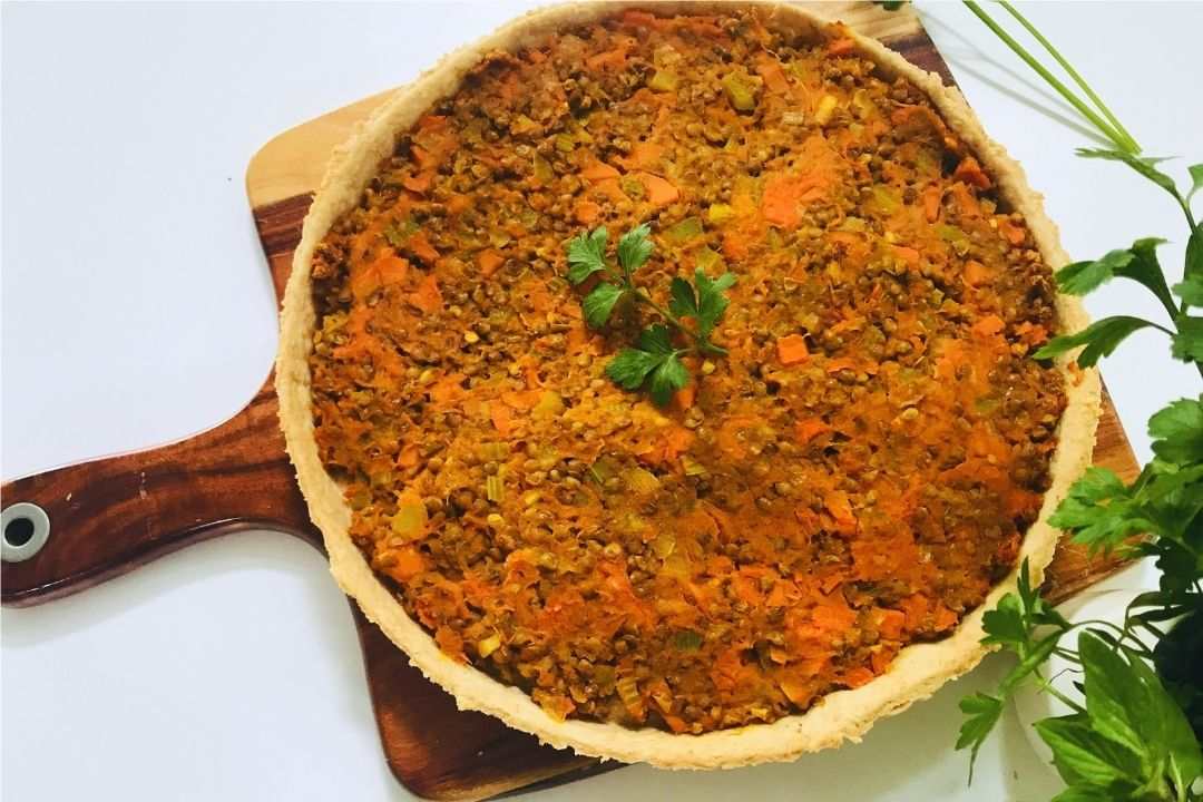 curried pumpkin and lentil pie baked on a wooden board with parsley as garnish 