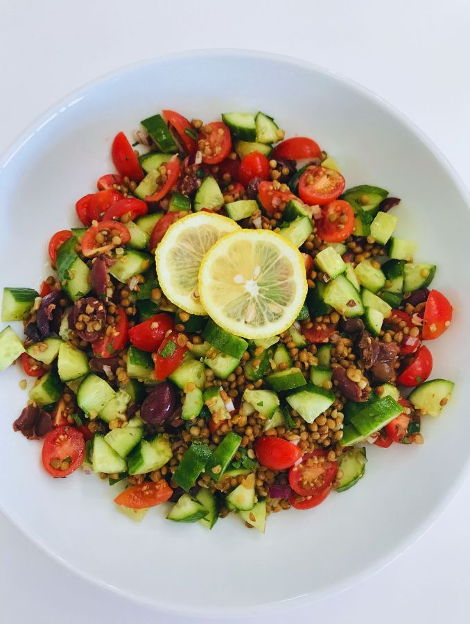 easy mediterranean lentil salad in a bowl with lemon garnish